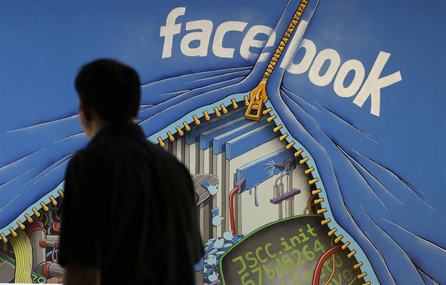 In this June 11, 2014 photo, a man walks past a mural in an office on the Facebook campus in Menlo Park, Calif. Facebook reports quarterly earnings on Tuesday, Oct. 28, 2014.