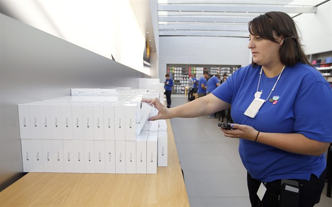An Apple employee grabs an iPhone 6 for a customer at the Apple Store during the launch and sale of the new iPhone 6 and 6 Plus smartphones, in Palo Alto, Calif.