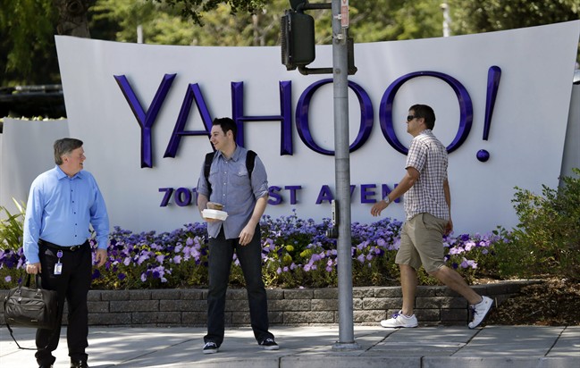 In this June 5, 2014 photo, people walk in front of a Yahoo sign at the company's headquarters in Sunnyvale, Calif. Yahoo Inc. reports quarterly financial results on Tuesday, Oct. 21, 2014.