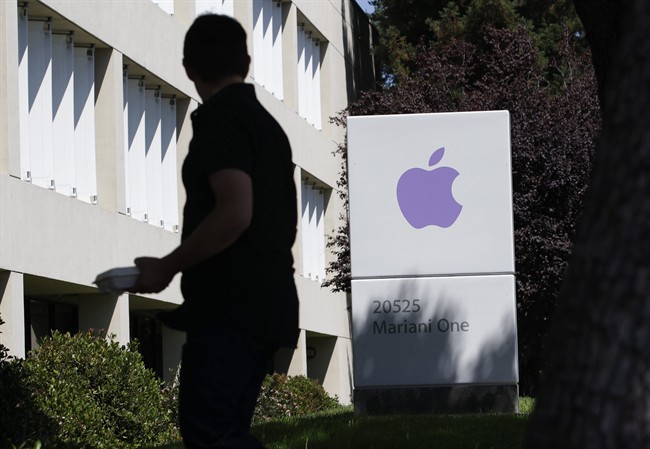 An Apple employee walks between Apple buildings at Apple headquarters in Cupertino, Calif. 
