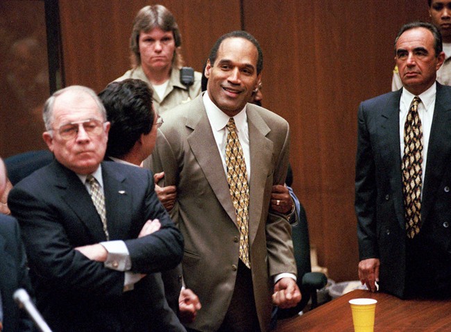 In this Oct. 3, 1995 file photo, O.J. Simpson, center, clenches his fists in victory after the jury said he was not guilty in the murders of his ex-wife Nicole Brown Simpson and her friend Ronald Goldman in a Los Angeles courtroom as attorneys F. Lee Bailey, left, and Robert Shapiro, right, look on.