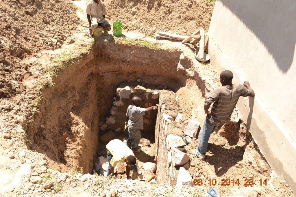 Workers digging a hole to add septic tanks for Tanzania orphanage.