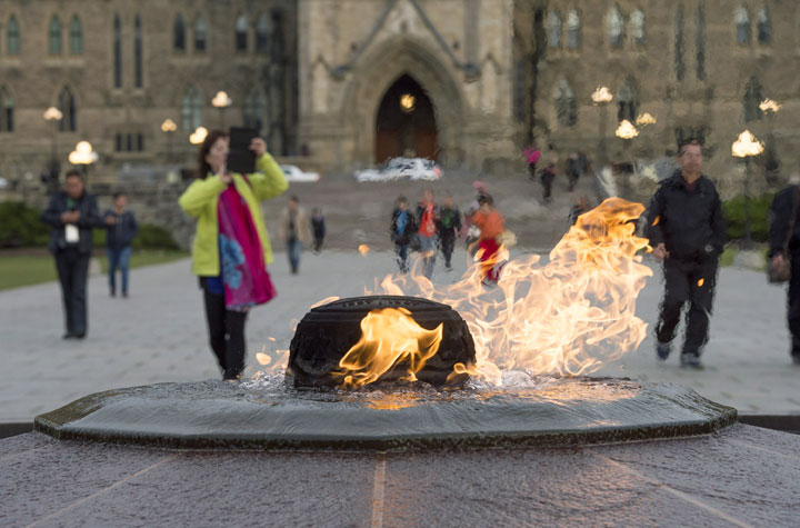 Visitors walk past the Centennial Flame on Parliament Hill in Ottawa on Saturday, Oct. 25, 2014. The grounds and lawn of Parliament Hill reopened Friday night following the shootings at the National War Memorial and inside Centre Block.