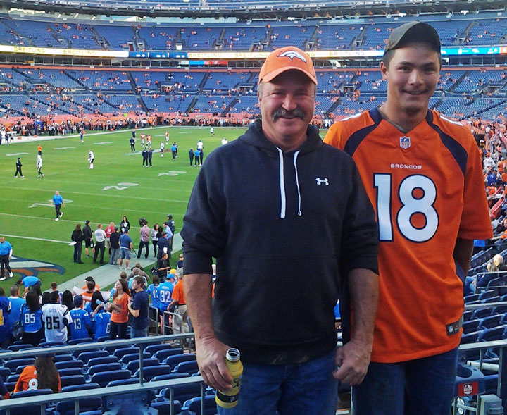 In this Oct. 23, 2014 photo provided by Jarod Tonneson, Paul Kitterman, left, and his stepson Jarod Tonneson pose for a photo during a San Diego Chargers-Denver Broncos football game at Sports Authority Field in Denver.