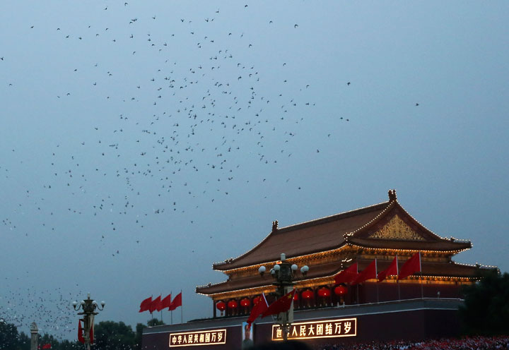 Doves fly over Tiananmen Gate after the flag raising ceremony on the National Day, the 65th anniversary of the founding of the People's Republic of China, in Beijing Wednesday, Oct. 1, 2014.
