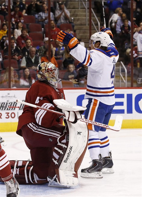 Edmonton Oilers' Taylor Hall (4) raises his arms in celebration after scoring a goal against Arizona Coyotes' Mike Smith, left, during the first period of an NHL hockey game Wednesday, Oct. 15, 2014, in Glendale, Ariz.