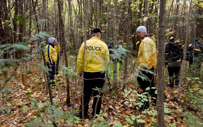 Police officers from Toronto Police and the OPP search a wooded area in Springwater Township, Ont., on Wednesday, Oct. 8, 2014. 