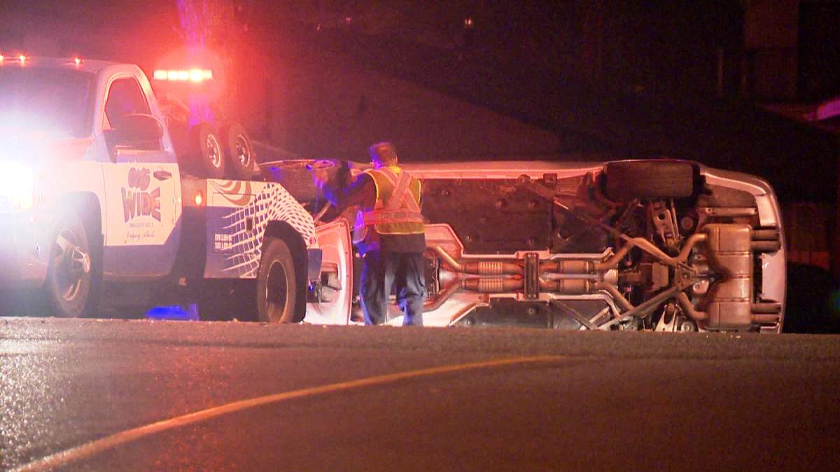 A tow truck operator attempts to remove a vehicle that had rolled in a southwest Calgary intersection on Thursday, October 30, 2014.