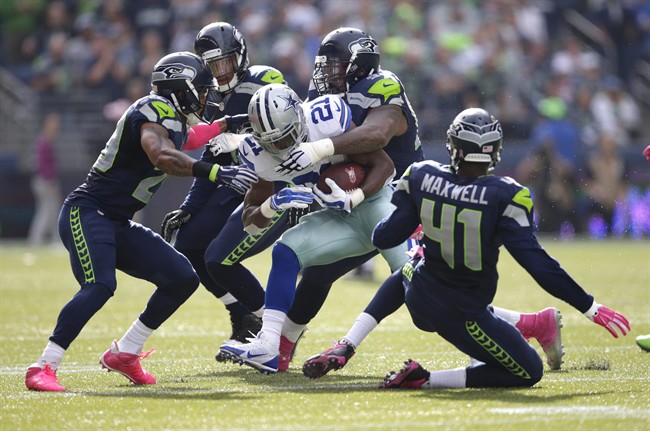 Dallas Cowboys running back Joseph Randle (21) is tackled by Seattle Seahawks defensive tackle Tony McDaniel, upper right, in the first half of an NFL football game, Sunday, Oct. 12, 2014, in Seattle. (AP Photo/Scott Eklund).