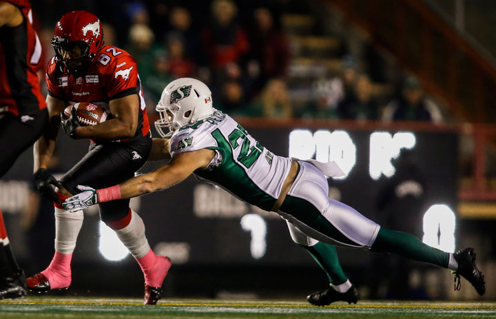 Saskatchewan Roughriders Brian Peters, right, dives after Calgary Stampeders Nik Lewis, during first quarter CFL football action in Calgary, Friday, Oct. 24, 2014.