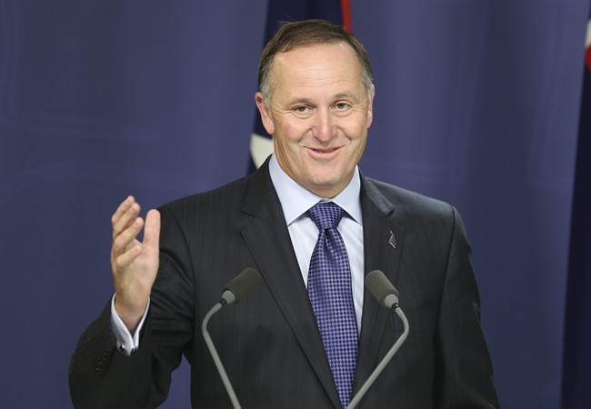 - In this Feb. 7, 2014 file photo, New Zealand Prime Minister John Key smiles while raising his hand as he speaks at a press conference.