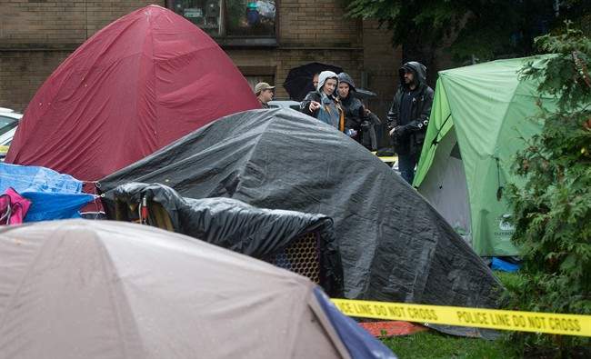 Police officers talk at the scene where a man was found dead at a tent city at Oppenheimer Park in the Downtown Eastside of Vancouver, B.C., on Wednesday October 15, 2014. A B.C. Supreme Court judge granted a court order last week allowing the city to clear tents and campers from the park after 10 p.m. Wednesday. The encampment began in July when people set up tents to bring attention to affordable housing in the city. THE CANADIAN PRESS/Darryl Dyck.