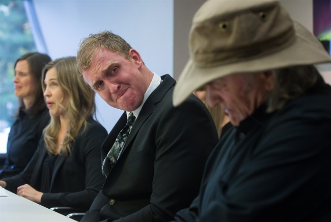 Peter de Groot's brother Miles de Groot, centre, fights back tears as he looks at his father Peter de Groot Sr., right, while his sister Danna de Groot, second left, reads a statement during a news conference in Vancouver, B.C., on Monday October 20, 2014. Forty-five-year-old Peter de Groot, the subject of a police manhunt in southern British Columbia was killed by members of the RCMP's emergency response team.