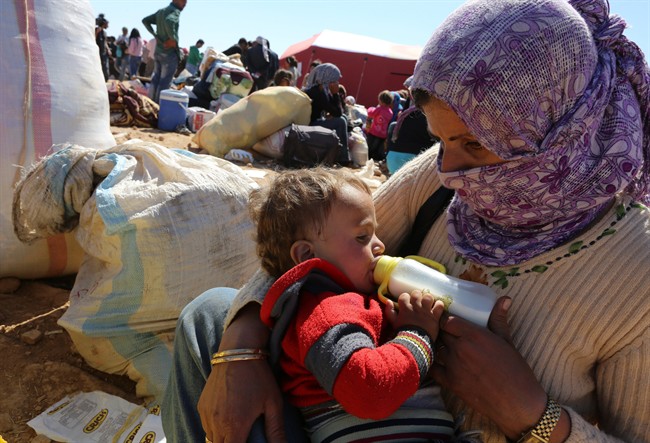 A mother feeds her baby as thousands of new Syrian refugees from Kobani arrive at the Turkey-Syria border crossing of Yumurtalik near Suruc, Turkey in Oct. 2014.