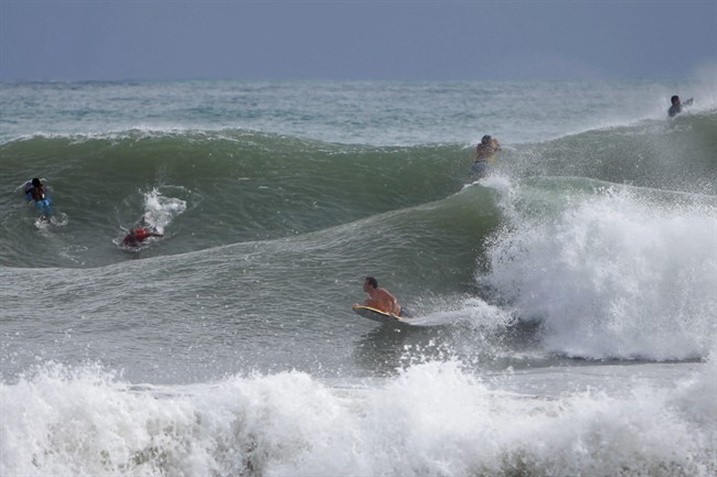 Surfers ride the waves in the waters at La Pared Beach in Luquillo, Puerto Rico