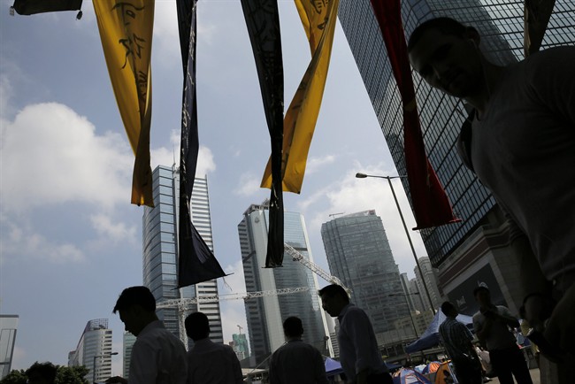 People walk past anti-government banner in an occupied area by pro-democracy protesters outside government headquarters in Hong Kong's Admiralty district Monday, Oct. 20, 2014.