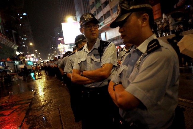 Local police stand guard during a face off between pro-democracy student protesters and angry local residents in Kowloon's crowded Mong Kok district, Friday, Oct. 3, 2014 in Hong Kong.