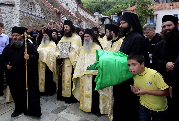A boy looks on next to Greek orthodox priests   as Russian Orthodox Patriarch Kirill I, takes part in a religious service outside the Protato chapel, near  Karies Monastery at the Orthodox monastic sanctuary of Mount Athos, in northern Greece, on Tuesday, June 4, 2012. 