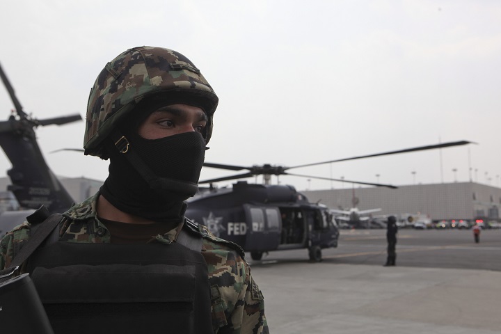 A Mexican navy marine stands guard as the helicopter carrying drug boss Joaquin "El Chapo"  Guzman prepares to take off from the navy hanger in Mexico City, Satuday Feb. 22, 2014.