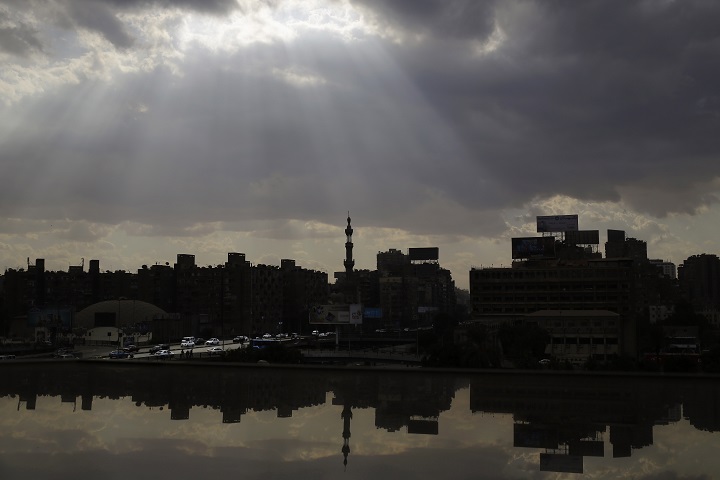 The sun's rays peep through the clouds over buildings in Giza, Cairo's neighboring city, seen through a window of a building in Cairo, Egypt, Friday, Oct. 31, 2014.