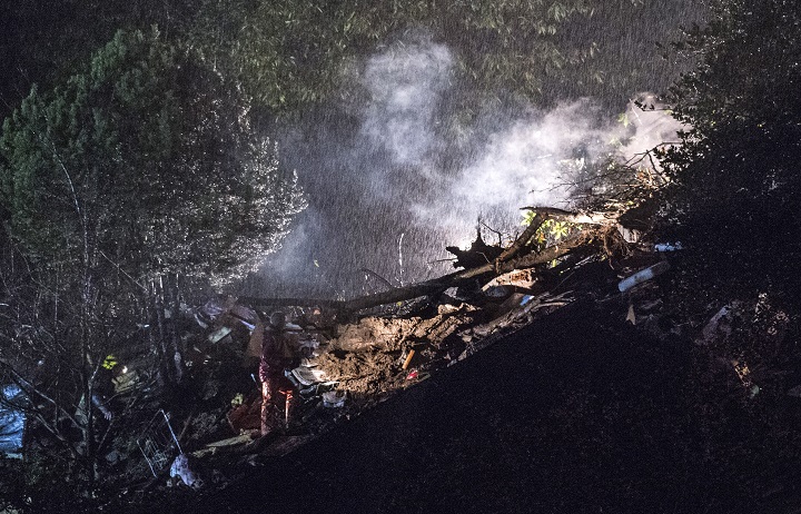 Rescue workers search in the rubble of a house that was destroyed in a landslide in Bombinasco, southern Switzerland, Wednesday evening, Nov. 5, 2014. A woman and her three-years-old child were found dead later in the building.
