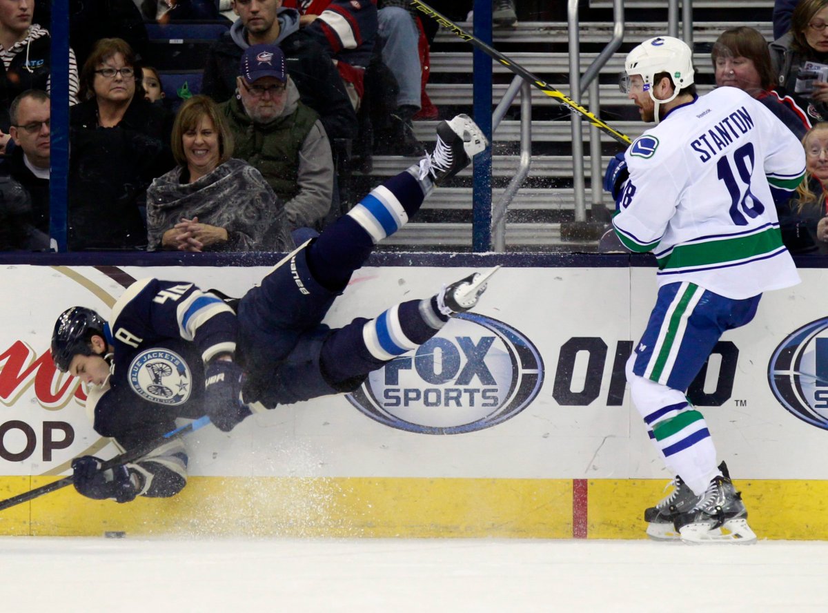Columbus Blue Jackets' Jared Boll, left, trips in front of Vancouver Canucks' Ryan Stanton during the first period of an NHL hockey game in Columbus, Ohio, Friday, Nov. 28, 2014. (AP Photo/Paul Vernon).