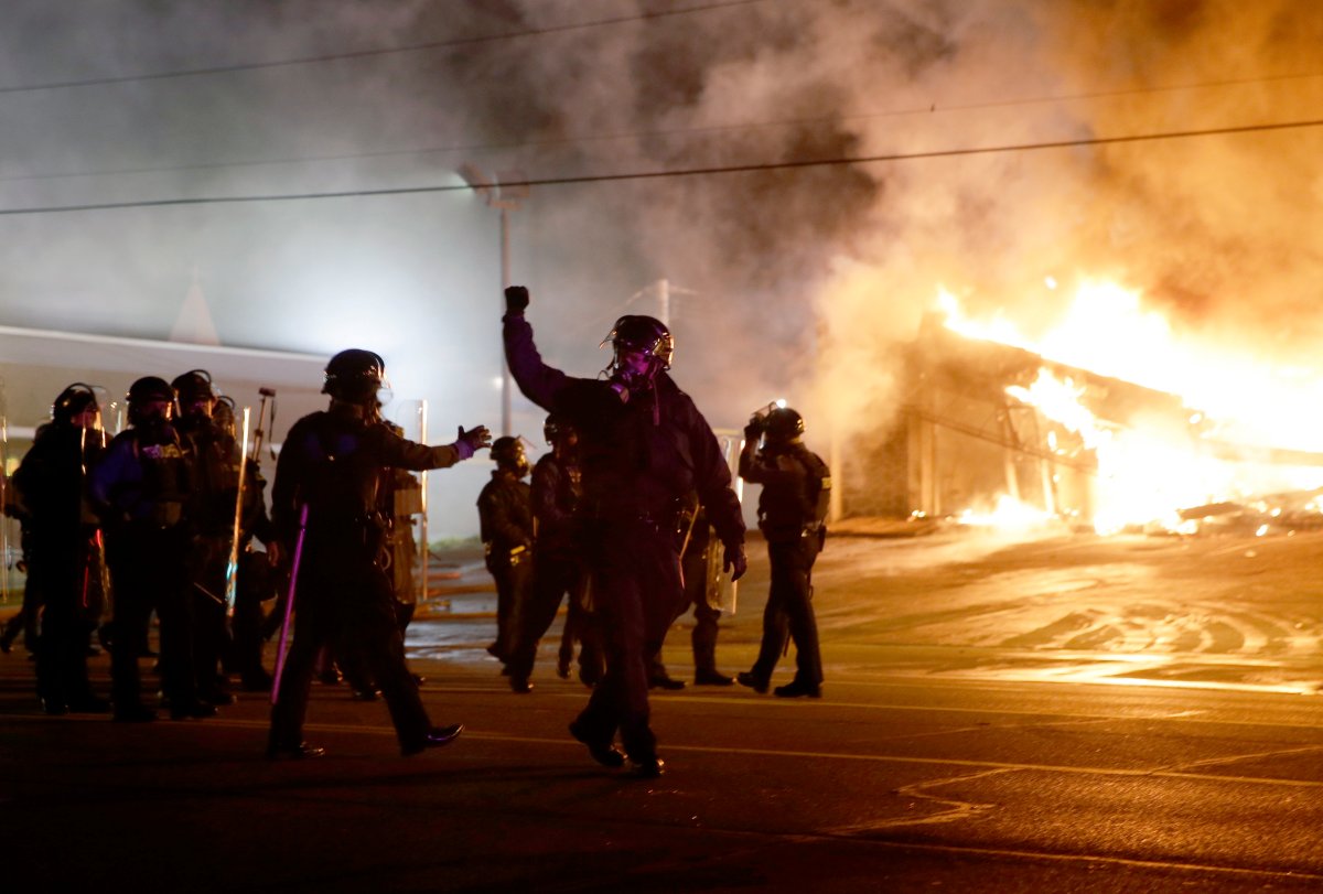 Police guard the area as some buildings are set on fire after the announcement of the grand jury decision Monday, Nov. 24, 2014, in Ferguson, Mo. A grand jury has decided not to indict Ferguson police officer Darren Wilson in the death of Michael Brown, the unarmed, black 18-year-old whose fatal shooting sparked sometimes violent protests. (AP Photo/David Goldman).