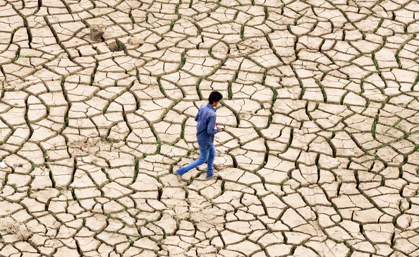An Indian youth walks over dried mud on the banks of a river after waters from the seasonal monsoon rains receded in Allahabad.