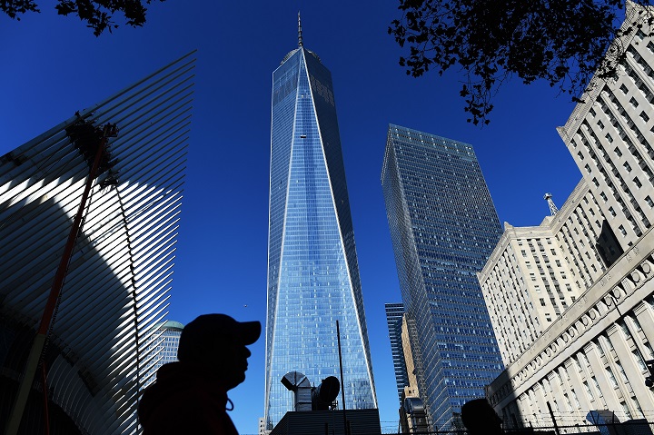 People walk past the construction site of the One World Trade Center in New York on October 17, 2014.