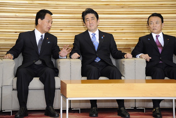 Japan's Prime Minister Shinzo Abe (C) listens to Economic Revitalization Minister Akira Amari (L) at a cabinet meeting at the prime minister's official residence in Tokyo on November 18, 2014, while Finance Minister Taro Aso (R) looks on.