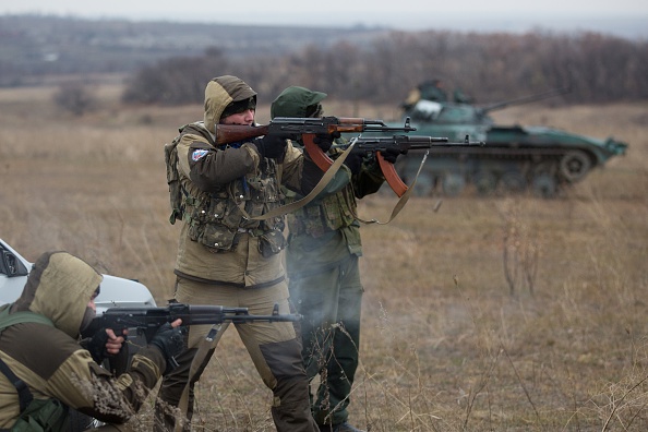 Pro-Russian militants fire their Kalachnikov asssault rifles  near an tank taken from Ukrainian forces during fighting in August, as they test fire in an open field, in the eastern Ukrainian town of Ilovaisk, some 40 kms east of Donetsk, on November 18 2014.  