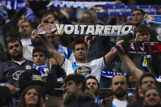 Coruna's fan displays a scarf reading "We will come back" during a Spanish La Liga soccer match between Atletico and Deportivo Coruna at the Vicente Calderon stadium in Madrid, Spain, Sunday, Nov. 30, 2014.