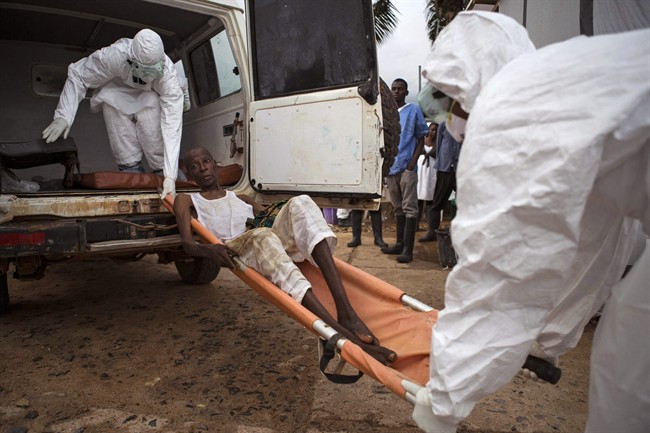 -In this file photo taken on Wednesday, Sept. 24, 2014, Healthcare workers load a man, center, onto a ambulance as he is suspected of suffering from the Ebola virus in Kenema, Sierra Leone.