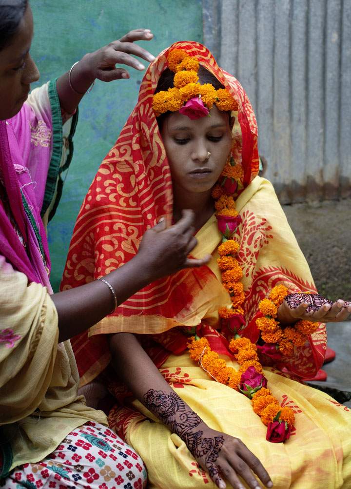A 14-year-old girl in Bangladesh is decorated with flowers and henna for her wedding.