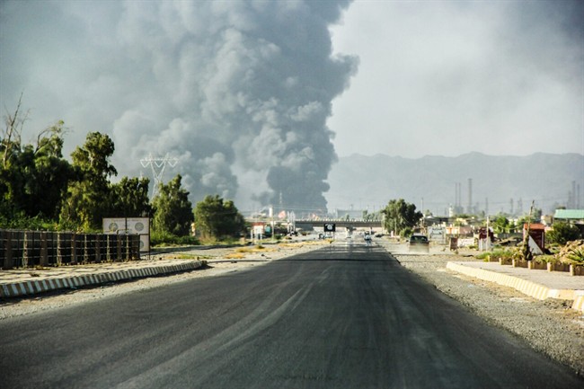 In this Thursday, July 31, 2014 file photo, a column of smoke rises from an oil refinery in Beiji, some 250 kilometers north of Baghdad. 