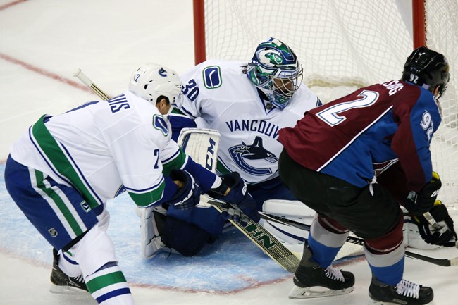 Vancouver Canucks goalie Ryan Miller, back, stops a shot off stick of Colorado Avalanche left wing Gabriel Landeskog, front right, of Sweden, as Canucks defenseman Dan Hamhuis covers in the second period of an NHL hockey game in Denver on Tuesday, Nov. 4, 2014. (AP Photo/David Zalubowski).