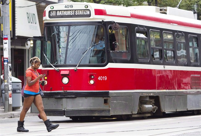 A pedestrian walking in front of a streetcar in downtown Toronto.