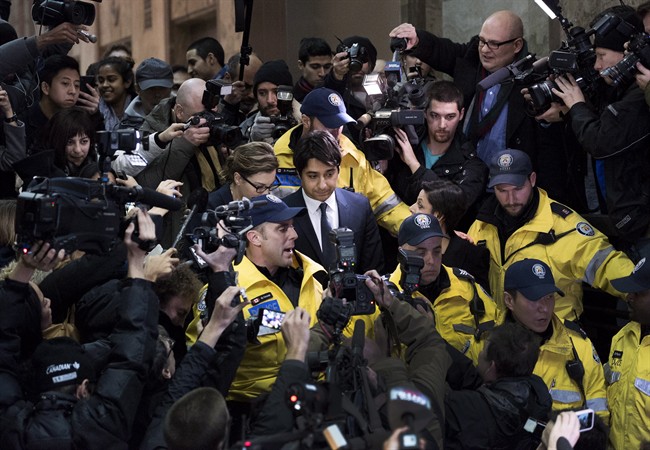 Former CBC Radio host Jian Ghomeshi, centre, is escorted out of court after being released on bail in Toronto on Wednesday, November 26, 2014. 