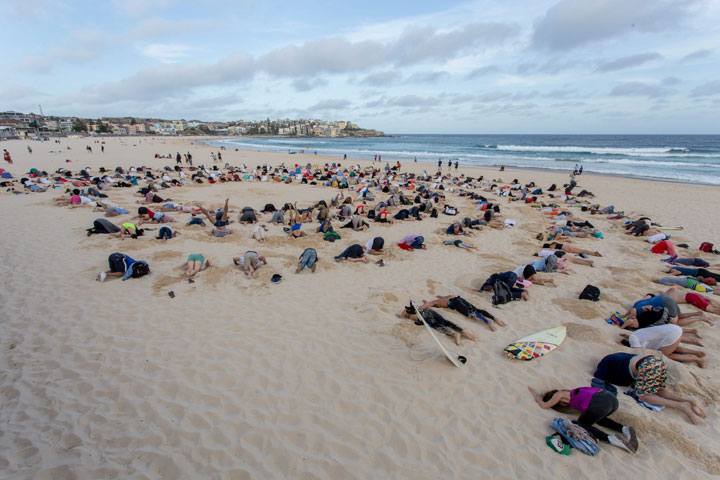 Sydneysiders bury their heads in the sand at Bondi Beach on November 13, 2014, as part of a protest of Prime Minister Tony Abbott's refusal to prioritise discussions of climate change at the G20 Leaders Summit in Brisbane on November 15 and 16.