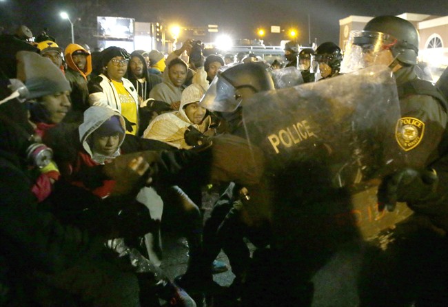 Police officers confront protesters Tuesday, Nov. 25, 2014, in Ferguson, Mo. Missouri's governor ordered hundreds more state militia into Ferguson on Tuesday, after a night of protests and rioting over a grand jury's decision not to indict police officer Darren Wilson in the fatal shooting of Michael Brown, a case that has inflamed racial tensions in the U.S.