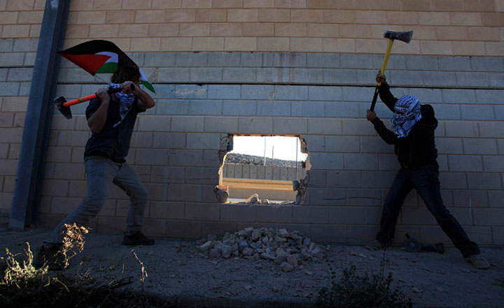 Palestinians make a hole in Israeli West Bank barrier, separating Israel and the West Bank, one day before the 25th anniversary of the fall of Berlin Wall near Bi’r Nabala neighborhood of Ramallah, West Bank on November 08, 2014.