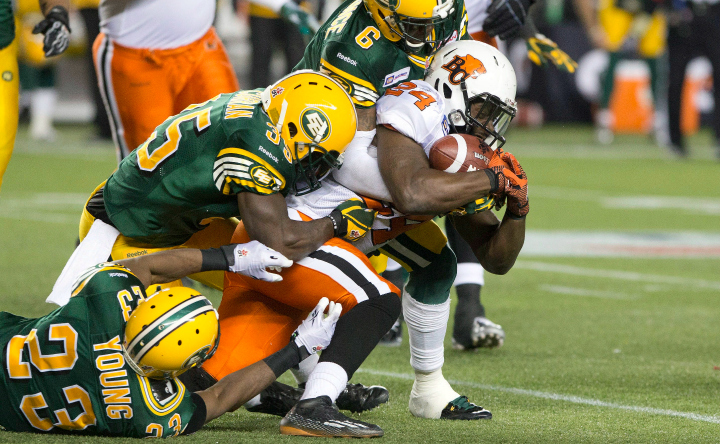 B.C. Lions Pascal Lochard (24) is tackled by Edmonton Eskimos Marcell Young (23), Rennie Curran (35) and Alonzo Lawrence (6) during second half CFL action in Edmonton, Alta., on Saturday November 1, 2014.