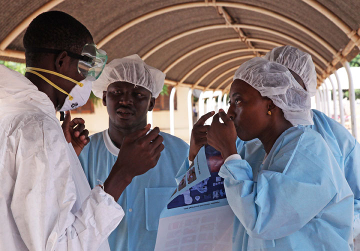 In this photo taken Saturday, Oct. 25, 2014, health workers are briefed on the use of their Ebola security gear before working with patients  at a Ebola virus centre in Kayes, Mali. 