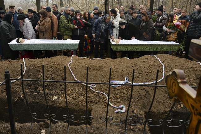 Relatives, teachers and schoolmates of 18-year-old Andrei Yeliseyev and 14-year-old Daniil Kuznetsov bid farewell during his funeral at a local cemetery in Donetsk, eastern Ukraine, Friday, Nov. 7, 2014. The rebel stronghold of Donetsk on Friday mourned the two teenagers who were killed in Wednesday's artillery strike on a high school on the city's western outskirts. (AP Photo/Mstyslav Chernov).
