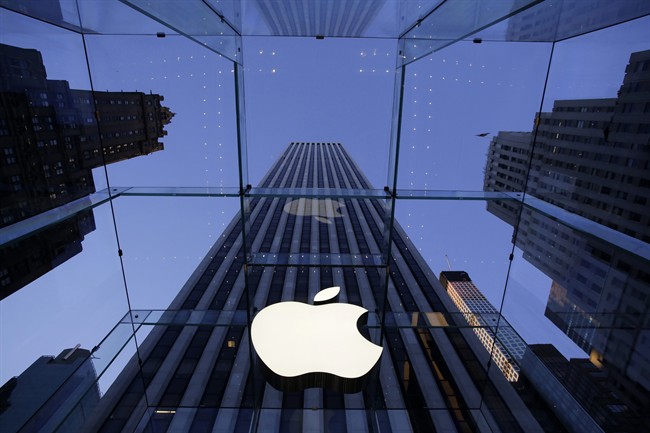 In this Sept. 5, 2014 file photo, the Apple logo hangs in the glass box entrance to the company's Fifth Avenue store, in New York. 