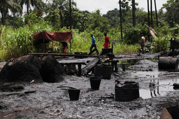 In this photo taken Saturday, May 18, 2013,  men walk past an abandoned  illegal refinery  at the creeks of Bayelsa, Nigeria.