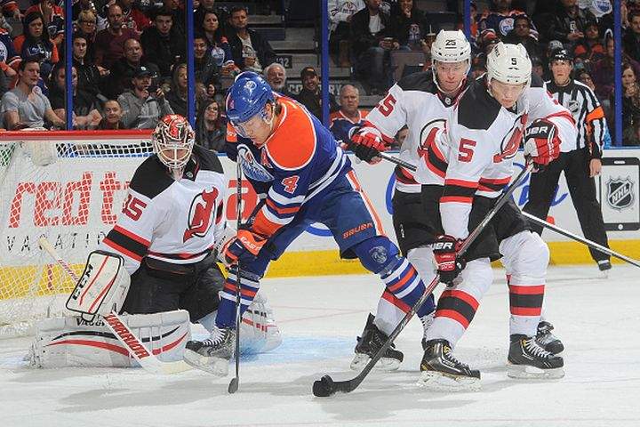 Taylor Hall #4 of the Edmonton Oilers battles for the puck against Adam Larsson #5 and Seth Helgeson #25 of the New Jersey Devils on November 21, 2014 at Rexall Place in Edmonton, Alberta, Canada.