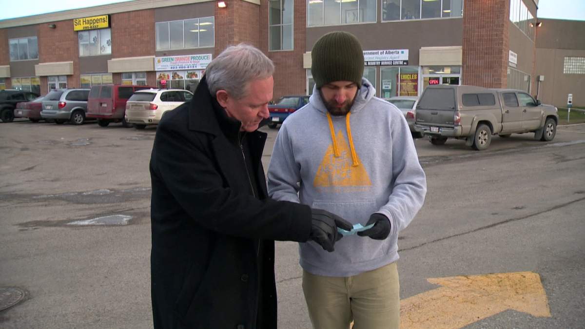 Reporter Tony Tighe (left) looks at a parking ticket Calgarian Matt Hala found on his windshield.