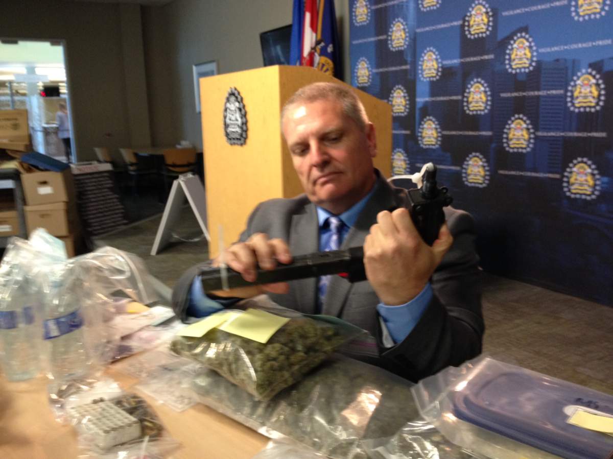 A Calgary police officer holds one of the weapons seized from a southwest home.