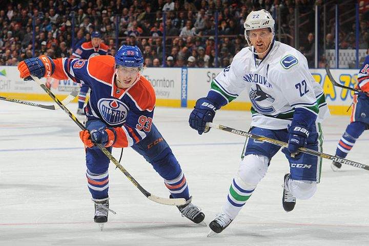 Ryan Nugent-Hopkins #93 of the Edmonton Oilers battles for the puck against Daniel Sedin #22 of the Vancouver Canucks on November 19, 2014 at Rexall Place in Edmonton, Alberta, Canada.